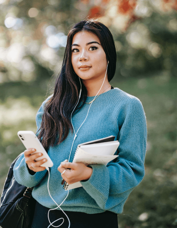 Foreign student listening to earphones to practice for her listening IELTS tests.