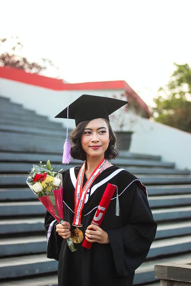 Female graduate holding a college degree.