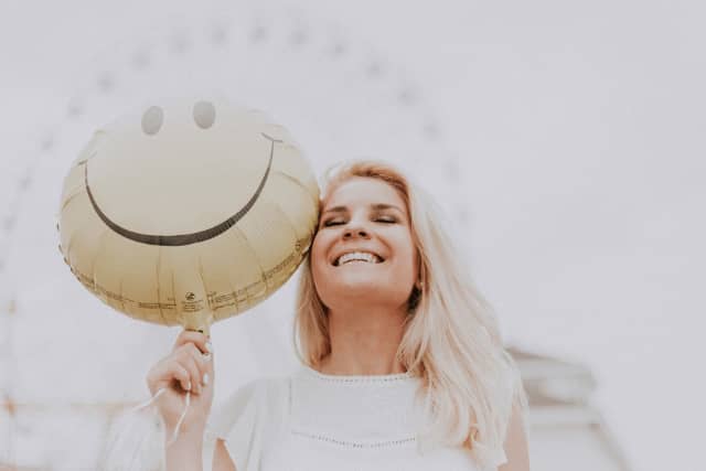 Girl with anxiety smiling while holding a balloon.