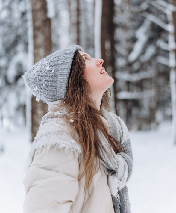 Girl in thick winter clothes under the snow.