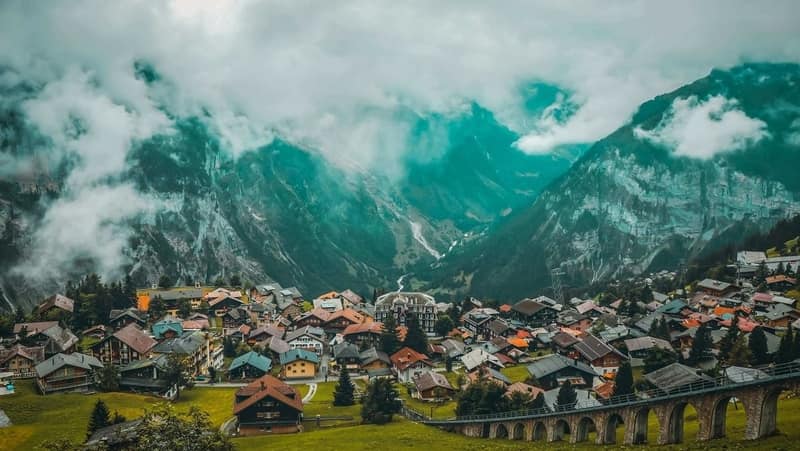 A scenic view of a hill station with houses amidst mountains