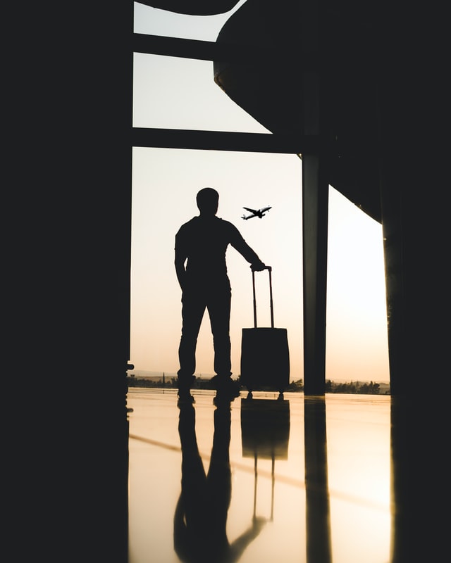 Man staring at airplane while holding luggage.