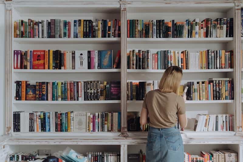 A girl arranging books on the shelf. 