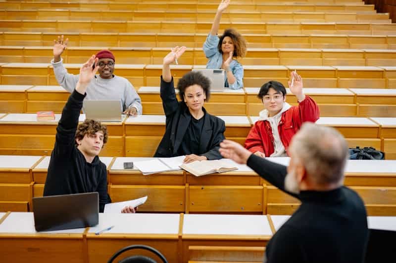  College students raising their hand in class. 